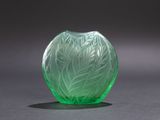 green glass vase sitting on top of a table with a black background