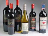 Plusieurs bouteilles de vin rouge et de vin blanc sont alignées en rangée