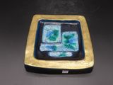 une petite assiette bleue et verte posée sur une table noire
