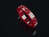 un bracelet rouge orné de rivets argentés sur un fond noir