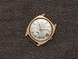 une montre en or posée sur un tissu noir, avec un cadran blanc
