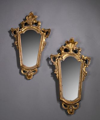 deux miroirs dorés ornés de motifs élaborés, posés contre un mur gris
