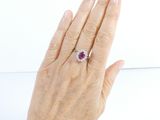 woman ' s hand with a diamond and ruby ring on it ' s finger