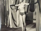 black and white photograph of a woman in a bathing suit holding a curtain