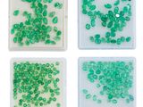 quatre types différents de perles en verre vert dans un plateau