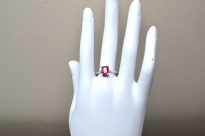 a hand with a ring on it that has a red stone on it
