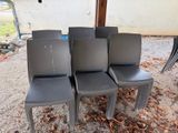 quatre chaises en plastique grises posées sur un sol recouvert de gravier