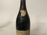 an old bottle of wine sitting on top of a white table