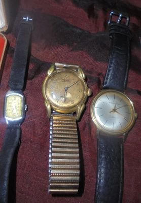 trois montres sont posées les unes à côté des autres sur un tissu rouge