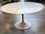 a white marble table with a black base on a tile floor
