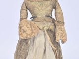une poupée ancienne représentant une femme vêtue d'une robe et d'un chapeau