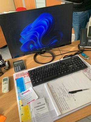 un bureau sur lequel se trouvent un ordinateur, un clavier, un téléphone et d'autres fournitures de bureau
