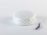 un récipient blanc avec une fleur violette à côté