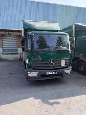 deux camions verts garés l'un à côté de l'autre devant un immeuble
