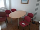 several chairs around a table in a room with a picture on the wall