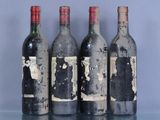 quatre bouteilles de vin sont alignées sur une table en verre