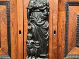 an antique wooden cabinet with a statue of a woman and a child