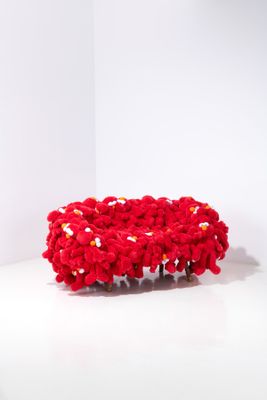 un bol rouge au crochet posé sur une surface blanche