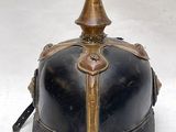 un vieux casque noir et or à la calotte pointue, sur fond blanc