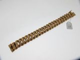 gros plan d'un bracelet en chaîne en or sur une surface blanche