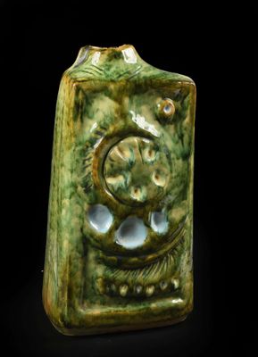 un vase vert orné d'un motif sur fond noir
