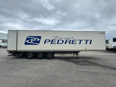 un semi-remorque blanc garé sur un parking à côté d'autres semi-remorques