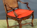 une vieille chaise en bois avec un coussin rouge posée sur un tapis vert