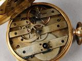 a gold pocket watch with a gold case on a white surface