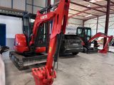 a red excavator that is parked inside of a building