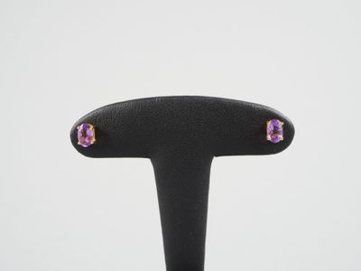 une paire de boucles d'oreilles en améthorate et saphir rose, présentées sur un socle noir