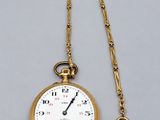 une montre de poche en or ancien, avec une chaîne suspendue sur le côté
