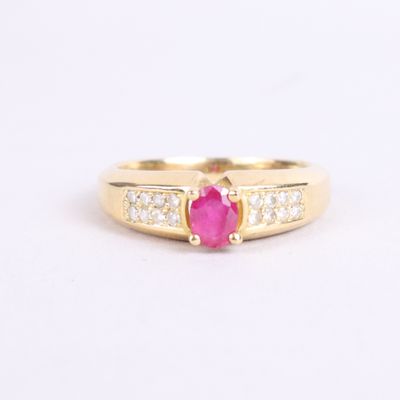 a close up of a gold ring with a ruby stone and diamonds