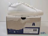 quelqu'un porte une paire de baskets blanches posées sur une boîte