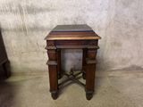 a small wooden table with a marble top on a cement floor
