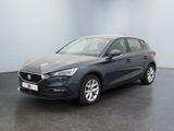 Une voiture grise est garée dans une pièce au sol noir.