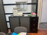 a desk with a printer, file cabinet, and chair in the room