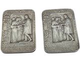 two silver metal plaques depicting a man and a woman holding a baby