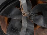 an old black helmet with a leather strap on a black background