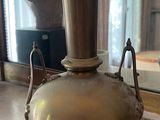 a large brass vase sitting on a table in front of a mirror