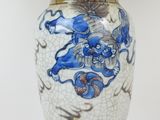a blue and white vase on a stand with a lamp on it