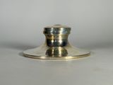 un bougeoir en argent posé sur une table blanche