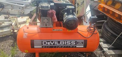 un compresseur d'air orange posé sur un tas de vieilleries