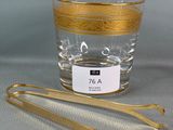 un verre à bord doré et une paire de pinces