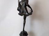 bronze statue of a woman holding a basket of flowers on a pedestal