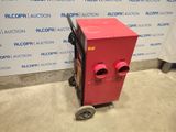 a red machine that is sitting in front of a wall