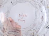 a person holding a glass bowl with writing on it