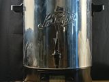 the large stainless steel pot is sitting on a wooden table