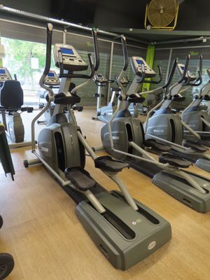 rows of stationary exercise bikes in a gym with a clock on the wall