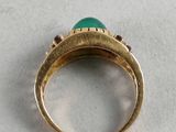 an image of a gold ring with a green stone in the middle