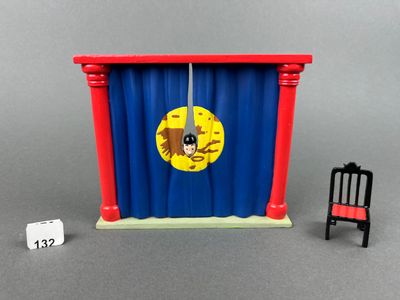 a toy chair and a chair in front of a curtain